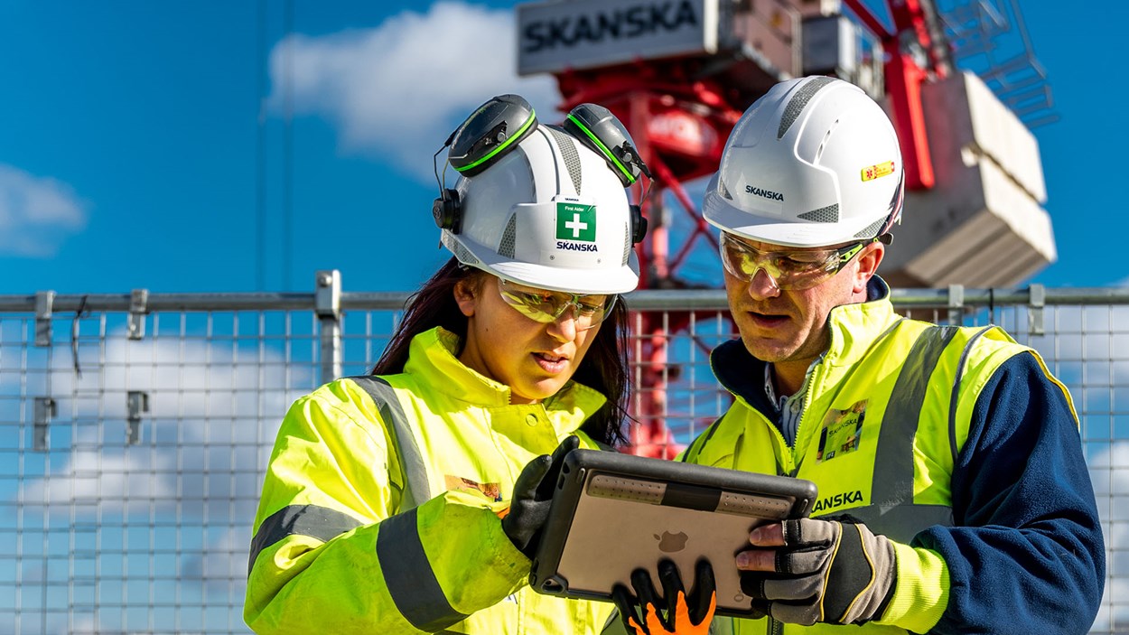 Two Skanska construction workers looking at a tablet on site