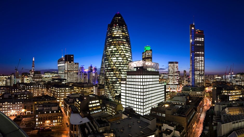 A range of office buildings in London, at night, with the skyline in the background