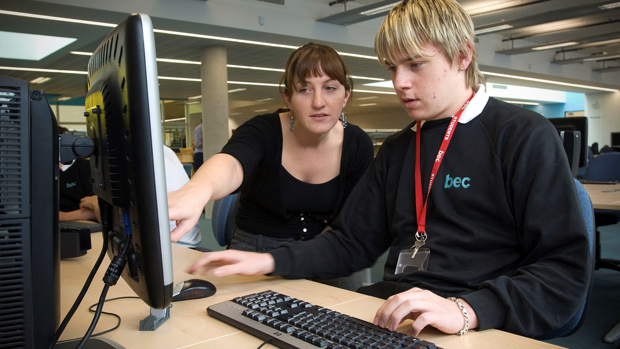 A teacher and a student at a computer in a classroom 