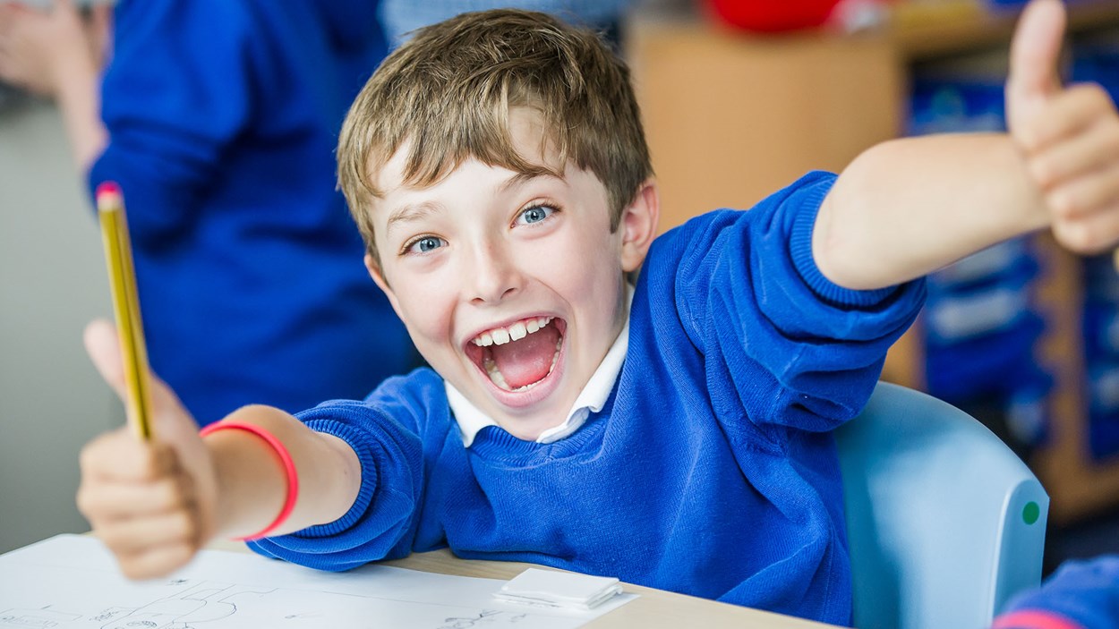 A happy  boy at in a primary school classroom, built by Skanska