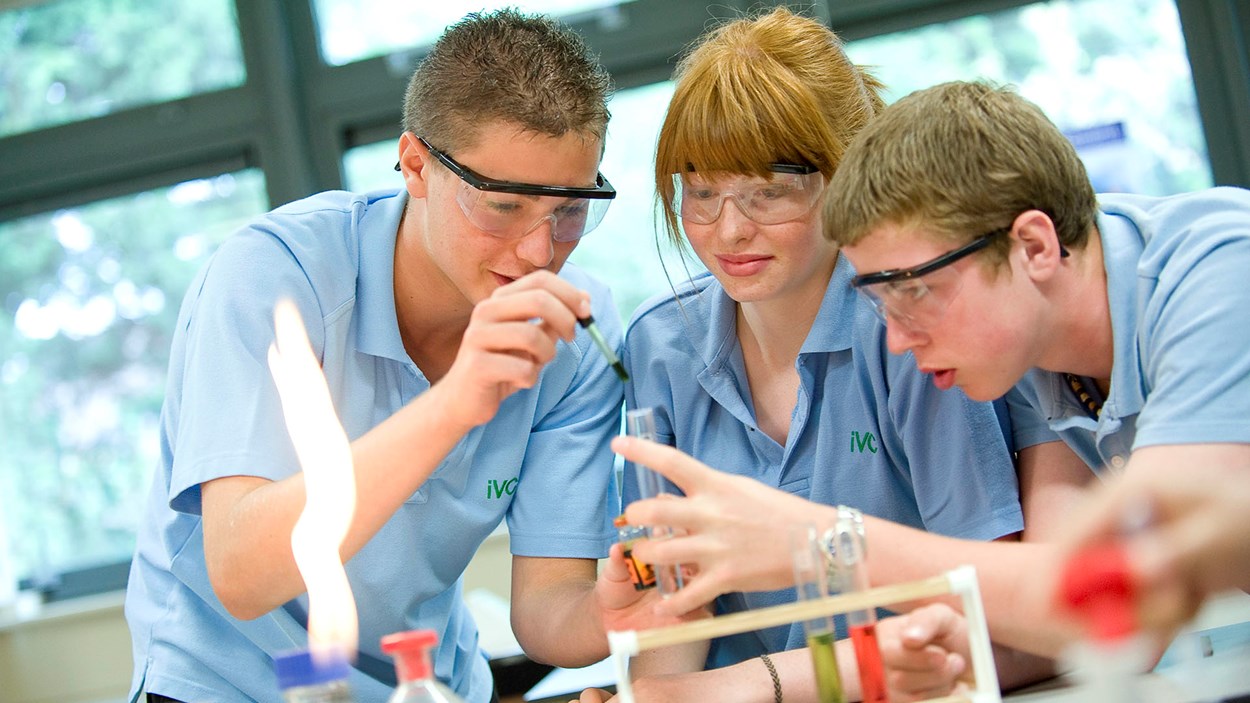 Two boys and a girl carrying out an experiment at a science class