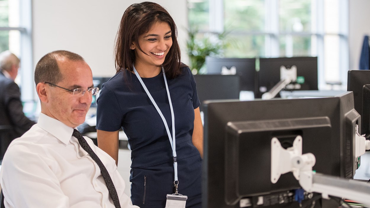 A man and woman looking a computer screen in an office