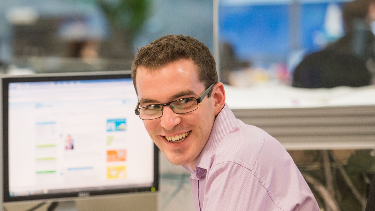 A happy man at work, with his desk behind him